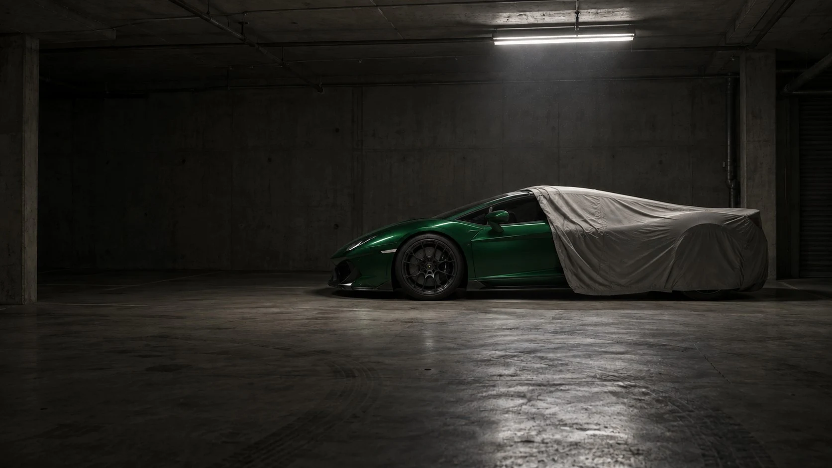 A green Porsche revealed from beneath a car cover
